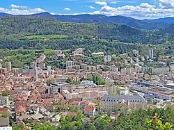 Photo d'une concentration de batiments dominés en arrière plan par une colline, prise d'un point de vue dominant.