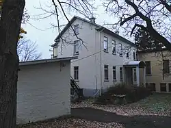 Une annexe de bâtiment de deux étages et demie de plan rectangulaire, revêtue de briques de couleur beige.