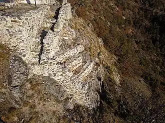 Carré de murs mi-hauts au dessus d'un précipice. Le mur qui donne dans le vide n'est plus là.