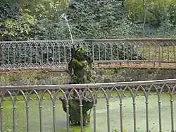 Vue d'une statue faisant office de jet d'eau, au centre d'un bassin.