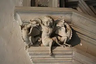 Photographie en couleurs d'un élément sculpté d'un escalier ancien.