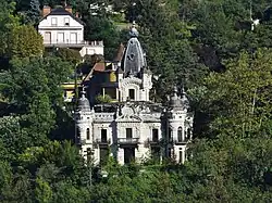 Photographie en couleurs d'un château émergeant des bois.