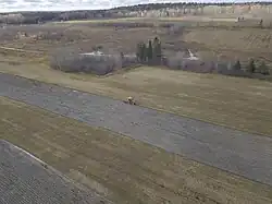 Un tracteur orange prépare le sol pour les prochaines cultures fourragères en 2024, photo par Kilian Bélisle