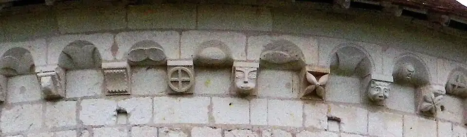 Photographie en couleurs montrant le détail des sculptures d'une corniche en pierre.