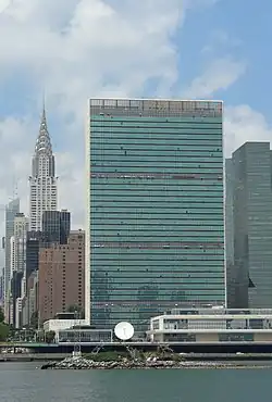 Photo représentant U Thant Island, avec le Chrysler Building et le siège des Nations unis en arrière plan. L'île est peu visible  du fait de sa taille modeste.