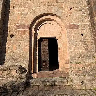 Le portail de l'église Sainte-Marie de Coustouges, construit avec une variété de pierres locales - granit gris et granit rose, conglomérat de couleur lie-de-vin, et grès