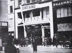 Photo noir et blanc de la façade avec une enseigne Cinébref en grandes lettres capitales et de nombreux piétons sur le trottoir devant le cinéma