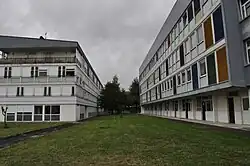 Deux bâtiments imposants encadrent l'image. À droite, le bâtiment Unesco se distingue par ses panneaux colorés, il abrite les enseignements généraux ; à gauche, le bâtiment De Moivre accueille l'internat.