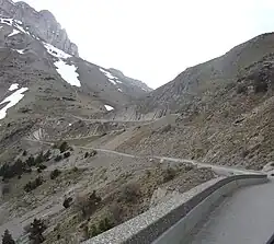 Photo d'une route en lacet au flanc d'une montagne dépourvue de végétation.