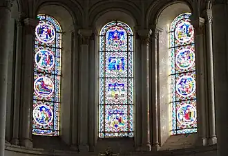 Photographie en couleurs de trois grandes verrières dans le chœur d'une église.