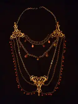 Long collier dit sautoir. La mode est au bijou fantaisie (laiton, verre, corail…).