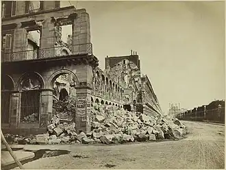 A gauche, des gravats surmontés de restes de murs gris formant une ligne oblique.