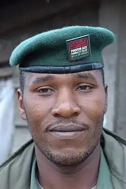 Sur l'insigne il est inscrit "Stop Rape Power to Women and Girls". L'insigne est l'emblème de la campagne lancée par l'UNICEF, V Day et d'autres organisations au Congo et dans le monde pour mettre fin aux viols dans les zones de conflit.