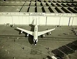 Cliché noir et blanc. Vue supérieure. Avion quadriréacteur sur un tarmac devant des hangars.