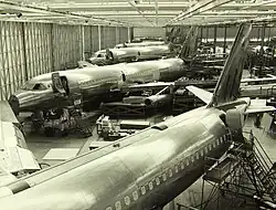 Cliché noir et blanc. Hangar. Quatre avions de trois quarts en cours de montage.
