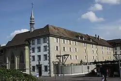 Photo de l'emplacement où se trouvait la Tour Jacquemert à Fribourg en 2011. On distingue le corps du bâtiment du couvent des Ursulines surmonté d'un petit clocher avec une croix. Le couvent des Ursulines est situé , 2 rue des Alpes à Fribourg, et à côté de ce bâtiment se trouvait la tour de Jacquemart, démolie en 1853. dans cette tour furent emprisonnées des personnes accusées de sorcellerie, dont le dénommé Bouquet, dénoncé par Catherine Repond. Des sorcières y auraient subi le supplice du quintal