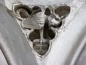 Photographie en couleurs d'une sculpture représentant un animal fabuleux posé sur la tête d'un enfant.