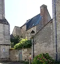 Photographie en couleurs d'un haut bâtiment au toit en ardoises, en arrière plan d'autre construction