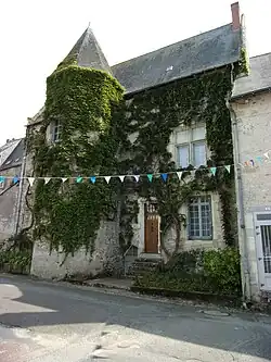 Photographie en couleurs d'un bâtiment à la façade partiellement couverte de végétation.