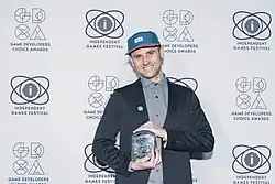 Photographie d'un homme souriant tenant un trophée ressemblant à un rectangle de verre.