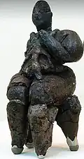 Déesse maîtresse des léopards, tenant un petit léopard sur sa poitrine, assise sur un léopard, terre crue, découverte dans une maison d'Hacılar, art néolithique, 5600 A.C., 13&nbsp;cm, musée des civilisations anatoliennes, Ankara, Turquie.