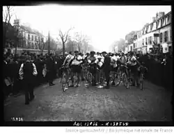 Photographie en noir et blanc présentant des cyclistes au départ d'une course.