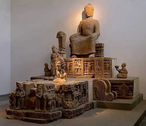 Bouddha du vihara (la pose des mains est un emprunt à la Chine des Tang) et assemblée bouddhique. À droite, moine porteur d'offrande. Fragments, Đồng Dương. Fin IXe - début Xe&nbsp;siècle.Musée de Đà Nẵng