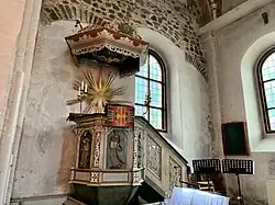 Pupitre baroque en bois sculpté, éclairé par vitraux colorés, ambiance spirituelle.