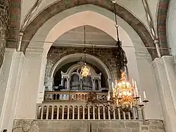 Intérieur d'église, orgue et lustre doré, lumière douce, ambiance solennelle.