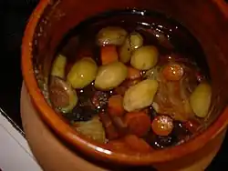Dans un plat en terre cuite vernissée, les morceaux de viande et de légumes (carottes, pomme de terre) ont mijoté dans le vin rouge.