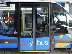 Photographie en couleurs des portes coulissantes fermées d'un minibus bleu et noir.
