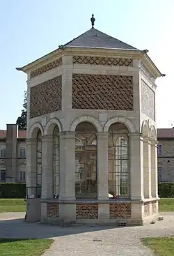 Petit bâtiment en pierre et brique avec arcades, surmonté d'un toit d'ardoises