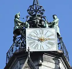Vue en contre plongée, d'une horloge au sommet d'un campanile, avec deux statues de chaque côté