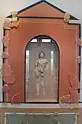 Photographie d'un petit autel en forme de niche renfermant une statuette.