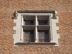 Photographie en couleur d'une fenêtre d'un bâtiment en briques rouges.