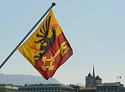 Le drapeau genevois suspendu au pont du Mont-Blanc avec la cathédrale Saint-Pierre en arrière plan.