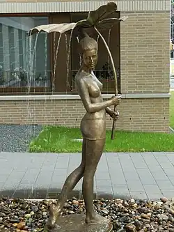 Fontaine représentant une jeune fille portant une feuille dont l'eau tombe tombe autour d'elle.