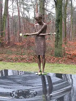 Sculpture en bronze d'un jeune fille en deuil, les bras croisés et la tête baissée.