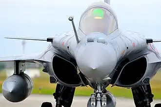 Vue de face d'un avion Rafale en train de rouler. Sur le nez de l'avion, devant la verrière et à côté de la perche de ravitaillement en vol, on distingue deux boules (une ronde à tribord, une avec des arrêtes plus marqués à babord) qui sont les deux capteurs de l'OSF.