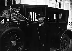 femme âgée devant une automobile, tenant un fanion "ACFF - Présidente"