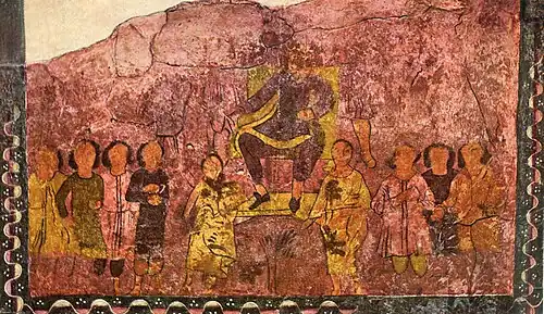 Un homme assis est porté par deux personnes et est entouré de plusieurs personnes.