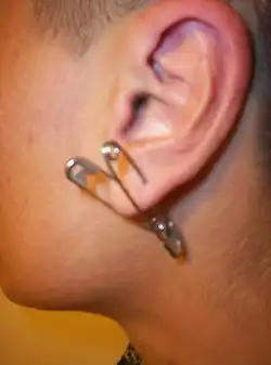 Oreilles avec épingle de sûreté en piercing.