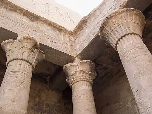 À g. colonne composite d'inspiration papyriforme. À dr. colonne à chapiteau lotiforme à corolle ouverte. Temple d'Horus (Edfou). De Ptolémée&nbsp;III à Tibère, 237-57.