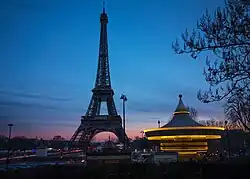 Photo de Paris la nuit, avec en toile de fond la Tour Eiffel et le Carrousel.