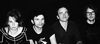 Photographie en noir et blanc de quatre musiciens.