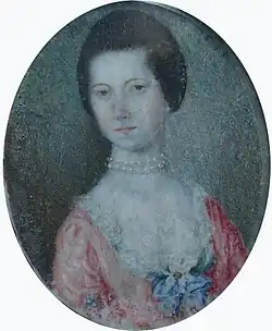 Portrait ovale d'une femme du XVIIIe siècle, en buste, avec une peau claire, coiffée d'un chignon. Elle porte une robe rose pâle avec dentelle blanche et un collier de perles.