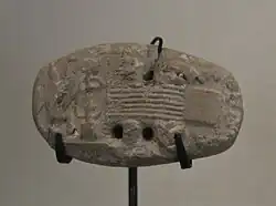 Petite tablette en forme de coussin avec une scène imprimée et des signes ronds.