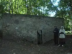Vue extérieure de l'enclos entourant la fontaine aux Moines, avec la porte d'entrée.