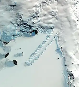 Image satellite de la baie Erebus montrant le glacier Erebus s'avançant dans la baie et entourée par les îles Dellbridge à gauche, la péninsule de Hut Point à droite et le reste de l'île de Ross en haut.