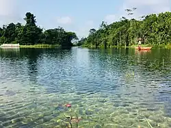 Une étendue d’eau claire avec un homme noir sur une barque.
